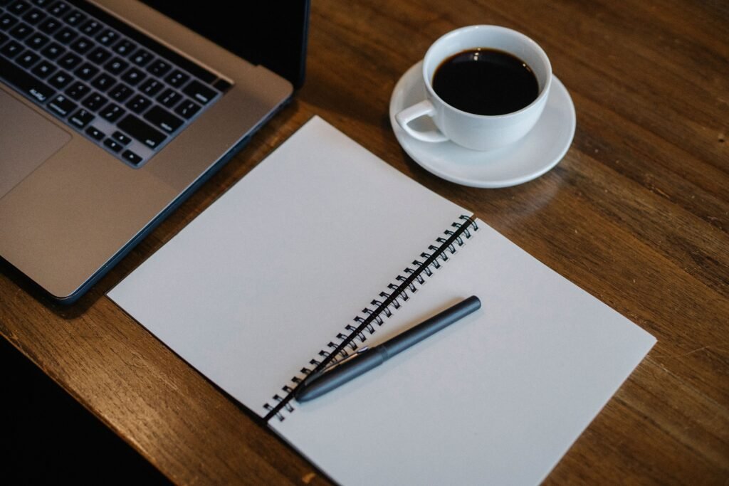 Cuaderno, computador portátil y taza de café sobre un escritorio de planificación